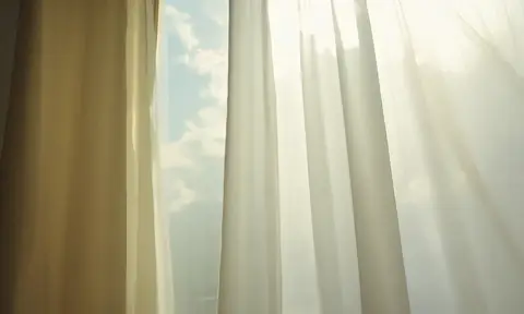 Morning sunlight streams through white curtains with a light breeze blowing